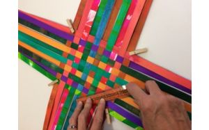 Image of the section of a basket in the making. it is being constructed with strips of different color papers.